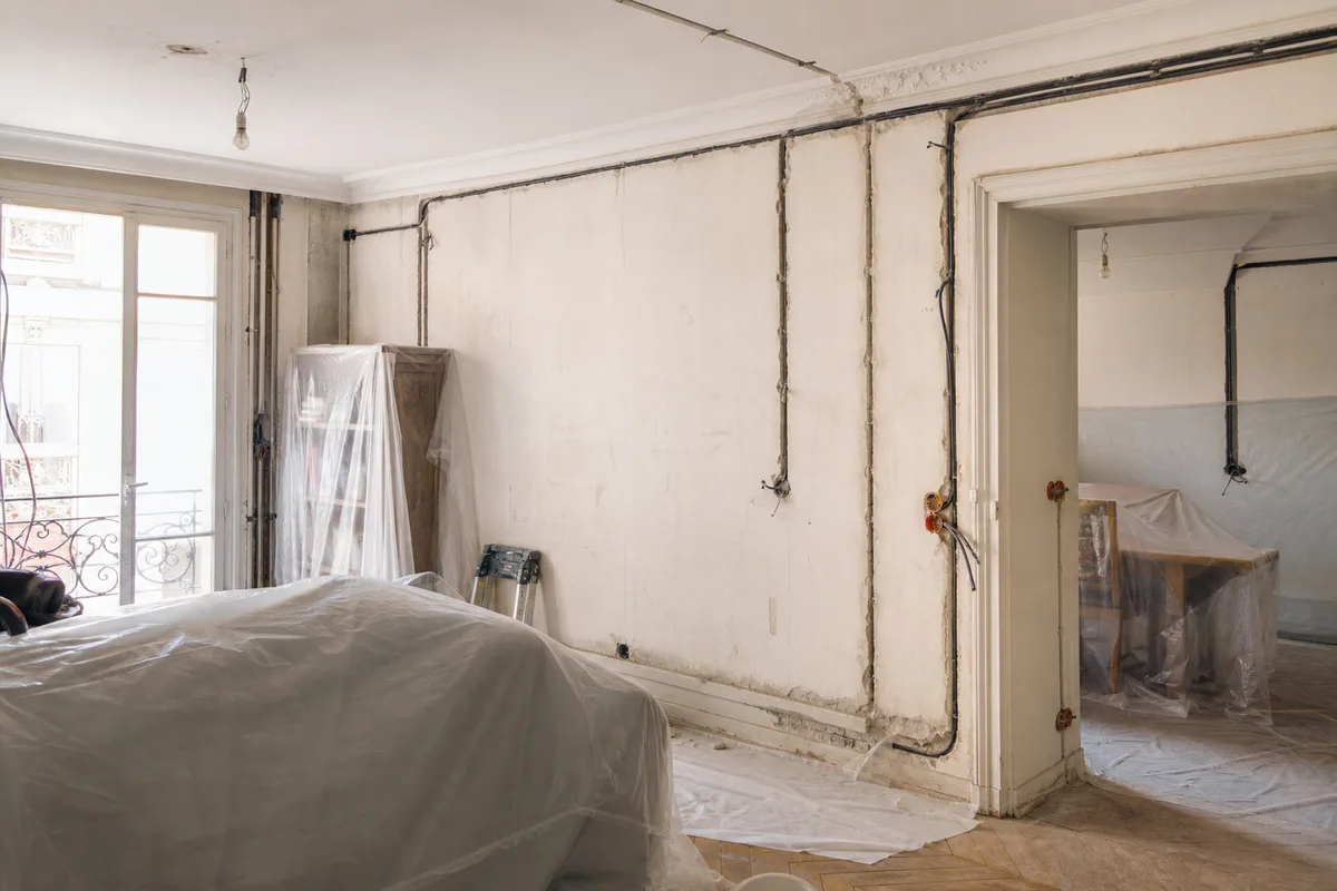 Chantier de rénovation dans un appartement habité, gaines électriques et saignées protégées par des bâches